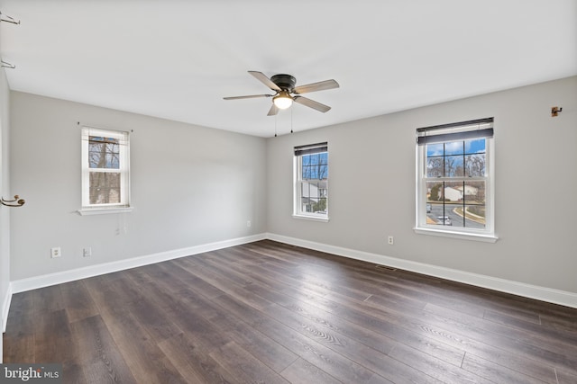 spare room featuring ceiling fan, dark hardwood / wood-style floors, and a wealth of natural light