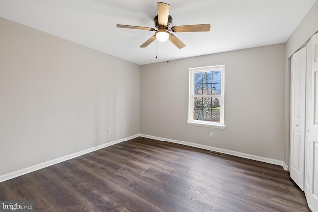 unfurnished bedroom featuring dark wood-type flooring, ceiling fan, and a closet