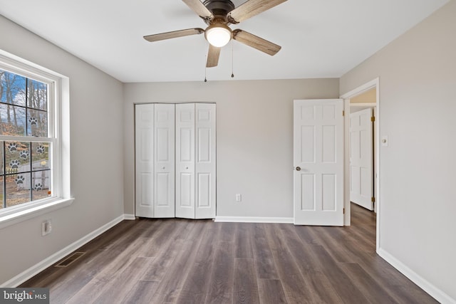 unfurnished bedroom featuring dark hardwood / wood-style floors, ceiling fan, and a closet