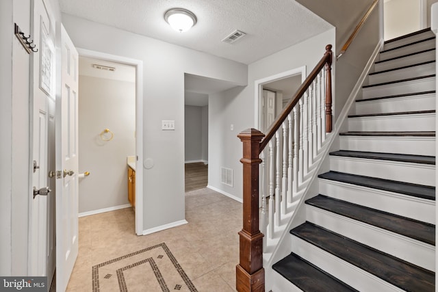 staircase with tile patterned flooring and a textured ceiling