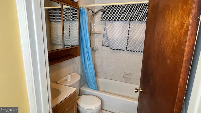 full bathroom with toilet, tile walls, vanity, and shower / bath combo with shower curtain