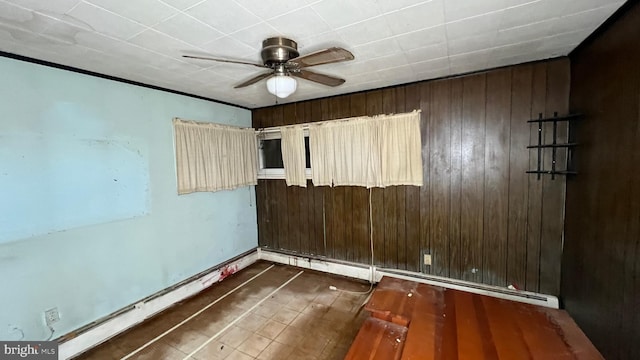 empty room featuring a baseboard heating unit and ceiling fan