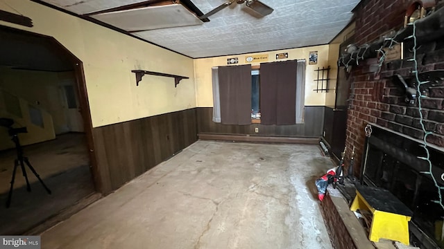 basement featuring a fireplace, wooden walls, and ceiling fan