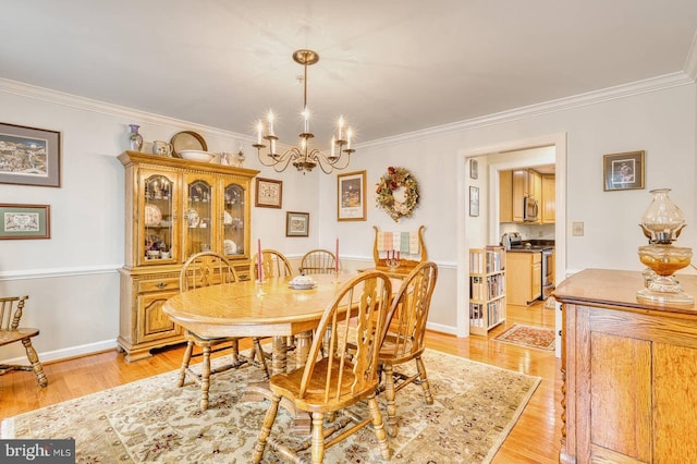 dining area featuring crown molding, a chandelier, and light hardwood / wood-style floors