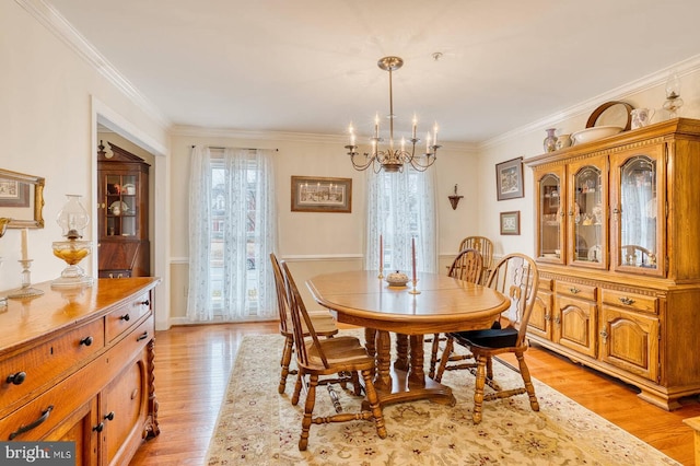 dining area featuring crown molding, a chandelier, and light hardwood / wood-style floors