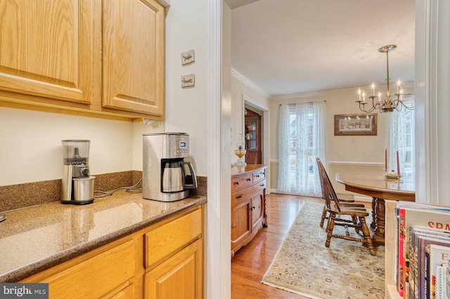 kitchen featuring light stone counters, light hardwood / wood-style floors, crown molding, light brown cabinets, and an inviting chandelier