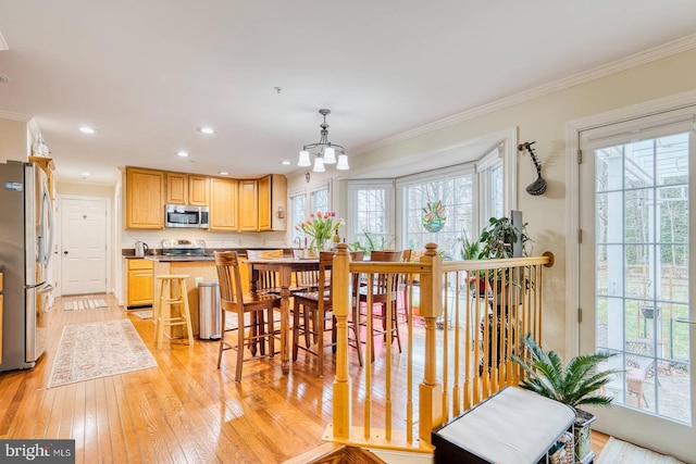 dining space with ornamental molding and light hardwood / wood-style floors