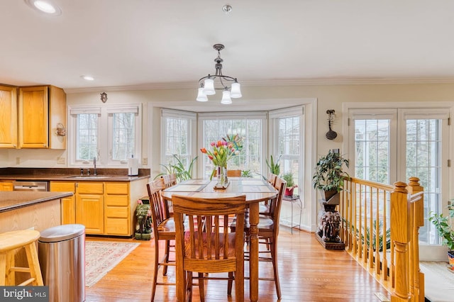 dining space with crown molding, a chandelier, light hardwood / wood-style floors, and sink