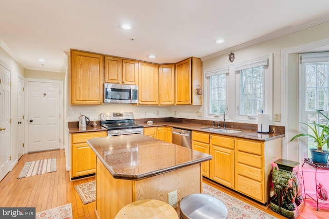 kitchen featuring appliances with stainless steel finishes, a center island, sink, and a wealth of natural light