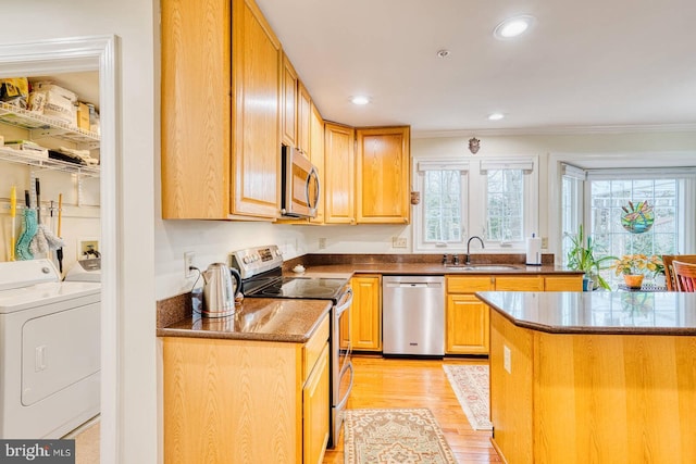 kitchen with appliances with stainless steel finishes, sink, ornamental molding, independent washer and dryer, and light wood-type flooring