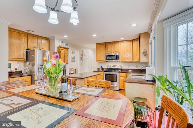 kitchen featuring appliances with stainless steel finishes, pendant lighting, sink, ornamental molding, and a center island