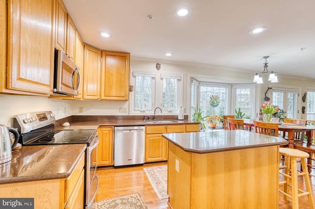 kitchen with a kitchen island, sink, hanging light fixtures, stainless steel appliances, and crown molding