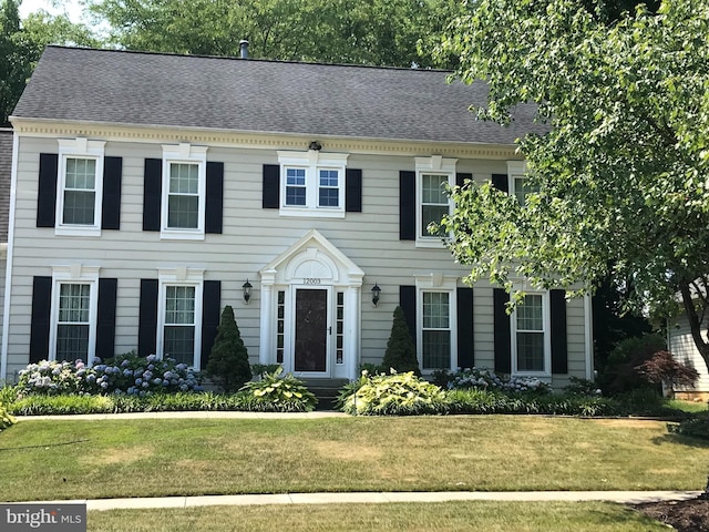 colonial inspired home with a front lawn