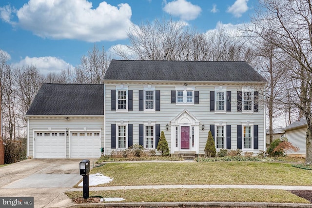 colonial-style house featuring a garage and a front lawn