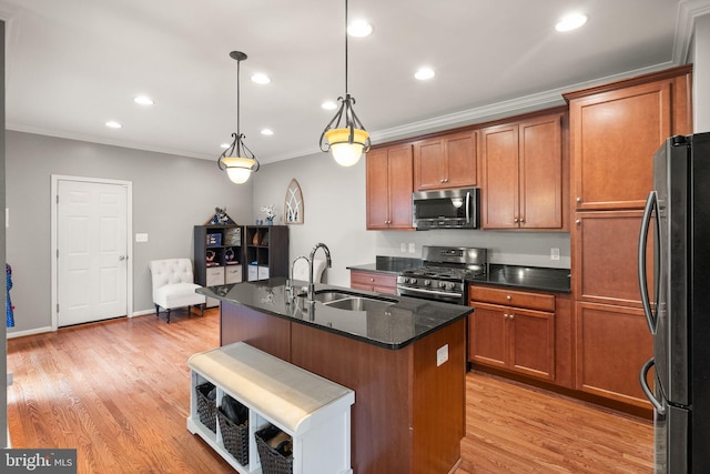 kitchen featuring sink, appliances with stainless steel finishes, ornamental molding, an island with sink, and decorative light fixtures