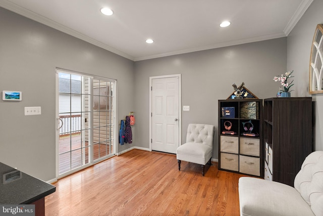 living area featuring crown molding and light hardwood / wood-style flooring