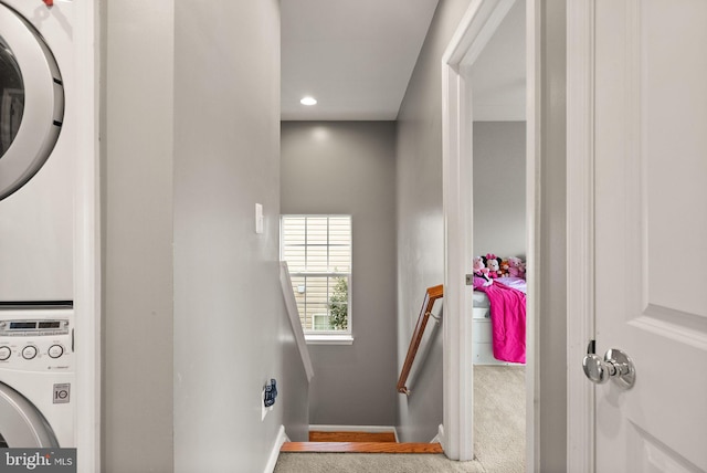 stairway featuring stacked washer and dryer and carpet