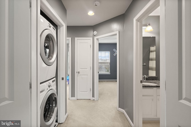 laundry area featuring stacked washer and clothes dryer, sink, and light colored carpet