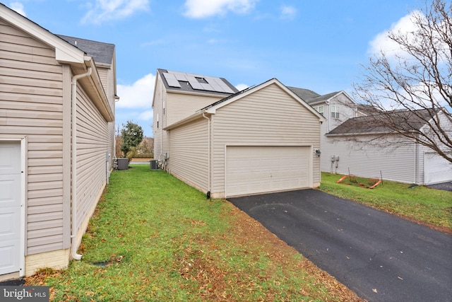 garage featuring central AC, a lawn, and solar panels