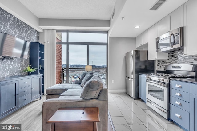 kitchen with white cabinetry, appliances with stainless steel finishes, tasteful backsplash, and a textured ceiling