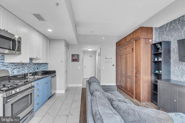 kitchen with stainless steel appliances, white cabinetry, sink, and tasteful backsplash