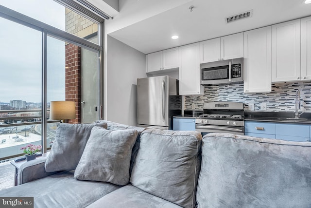 kitchen with appliances with stainless steel finishes, sink, white cabinets, and backsplash