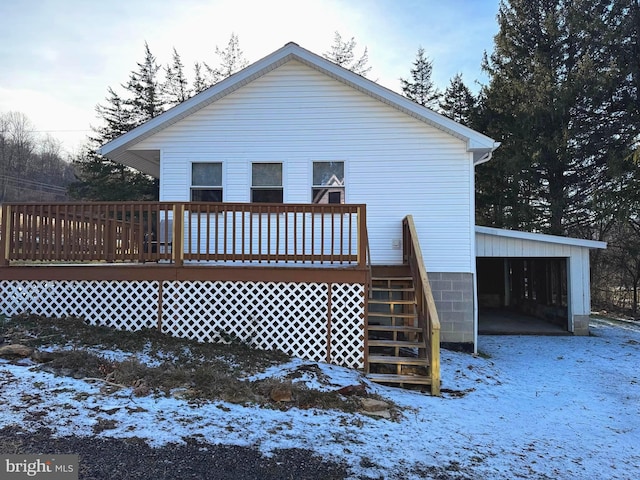 snow covered house featuring a garage and a deck