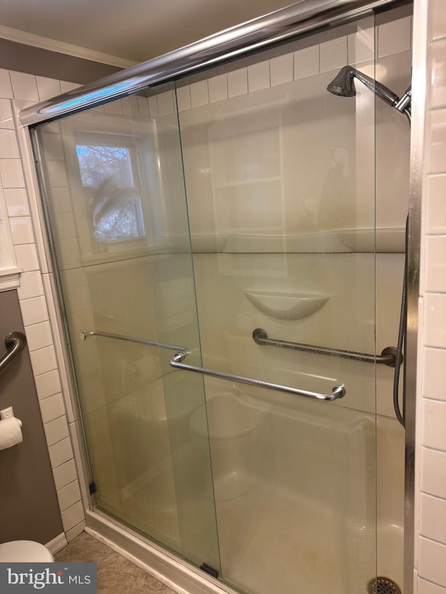 bathroom with ornamental molding and a shower with shower door