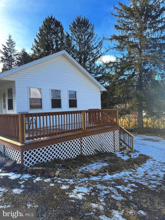 snow covered rear of property with a deck