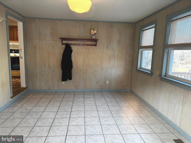 empty room featuring ornamental molding and light tile patterned floors