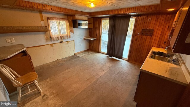 kitchen featuring light countertops, a sink, and wood walls