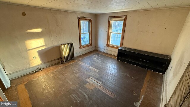 unfurnished room featuring dark wood-style flooring, ornamental molding, and radiator heating unit