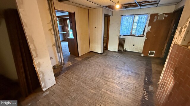 spare room with dark wood-style flooring and radiator heating unit