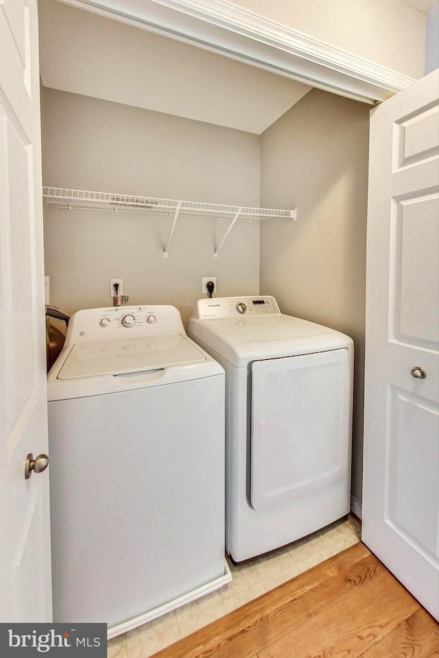 clothes washing area featuring washer and dryer and light wood-type flooring