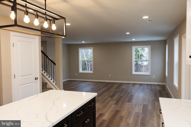 kitchen with decorative light fixtures, recessed lighting, open floor plan, light stone countertops, and dark cabinetry