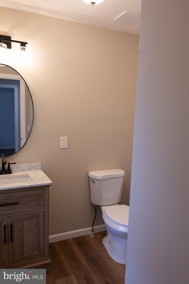 bathroom with baseboards, visible vents, toilet, wood finished floors, and vanity