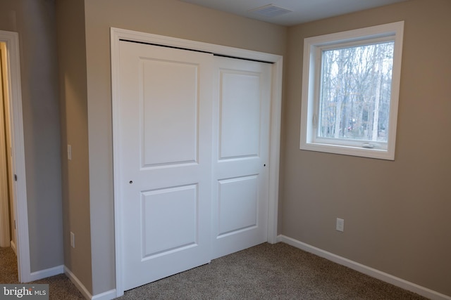 unfurnished bedroom with a closet, carpet flooring, visible vents, and baseboards