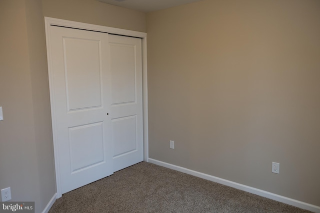 unfurnished bedroom featuring carpet floors, baseboards, and a closet