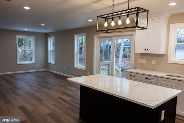 kitchen featuring white cabinets, a kitchen island, light stone counters, pendant lighting, and recessed lighting