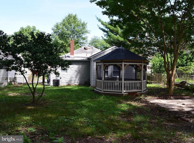 rear view of house with a gazebo, a yard, and central air condition unit