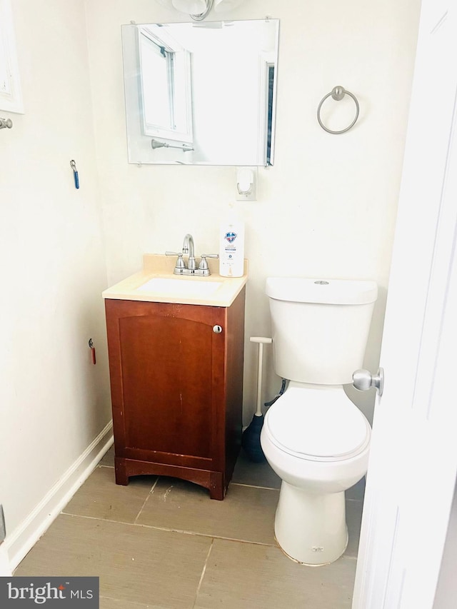 half bath with vanity, baseboards, and toilet