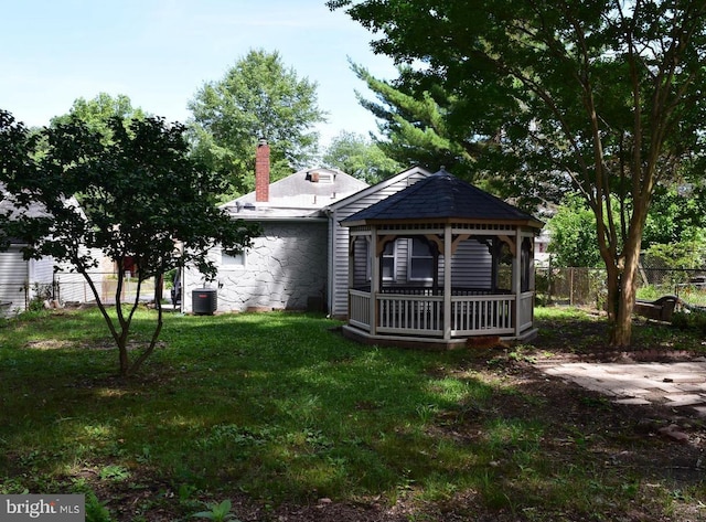 back of house featuring central AC unit, a yard, a gazebo, a chimney, and fence