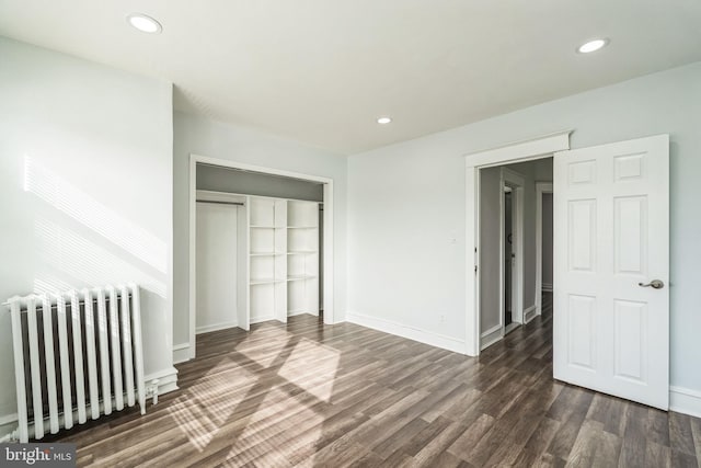 unfurnished bedroom with radiator heating unit, dark hardwood / wood-style flooring, and a closet