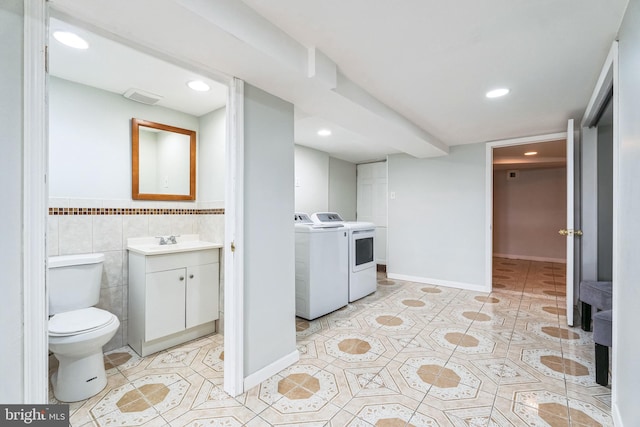 laundry area with washing machine and dryer, sink, light tile patterned floors, and tile walls