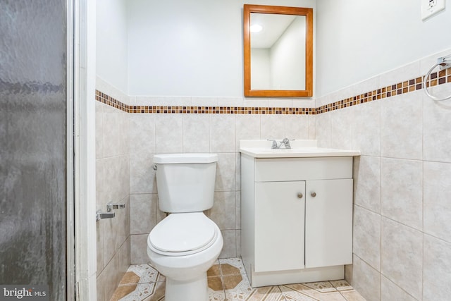 bathroom featuring vanity, tile patterned floors, toilet, and tile walls