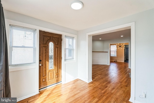 entrance foyer featuring an inviting chandelier, a wealth of natural light, and light wood-type flooring