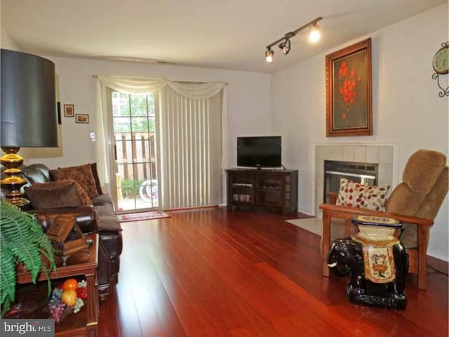 living room with a tile fireplace, hardwood / wood-style floors, and track lighting