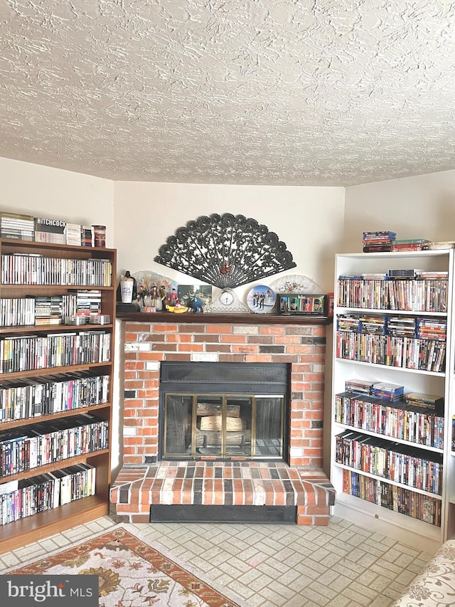 living room featuring a brick fireplace and a textured ceiling