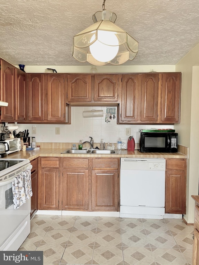 kitchen with sink, a textured ceiling, and white appliances