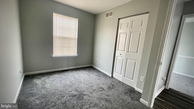 unfurnished bedroom featuring a closet and dark colored carpet